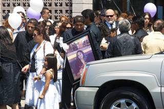 A man is seen carrying Yadira Martinez's portrait after the funeral service held for Martinez and her daughter Karla at St. Christopher Catholic Church on Friday, May 11, 2012.